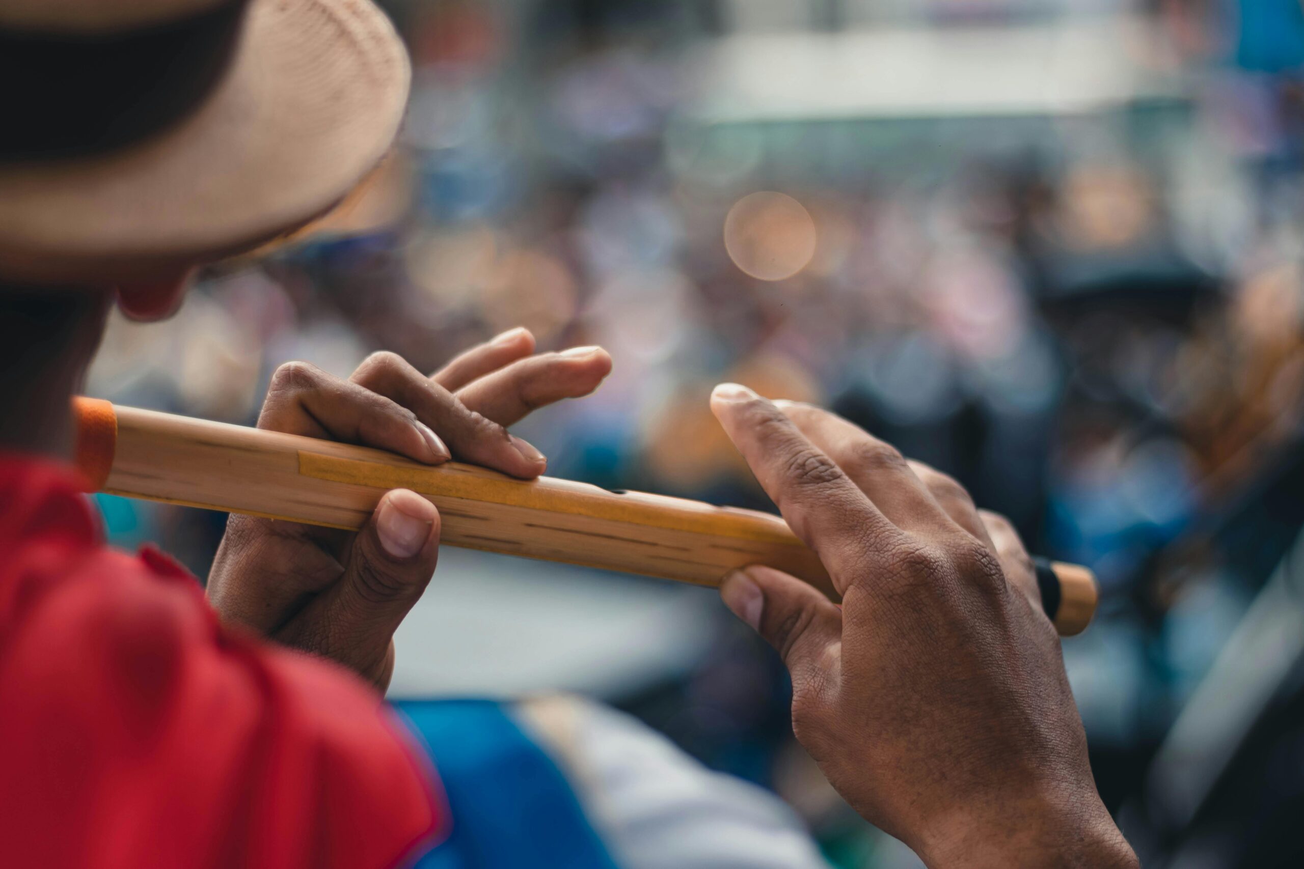 Close-up of a person playing a bamboo flute with blurred background in Popayán, Colombia.